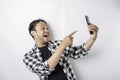 A portrait of a happy Asian man is smiling while holding on his phone, isolated by white background Royalty Free Stock Photo