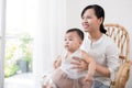 Portrait of happy asian mother and baby having fun together at home in white room, near window Royalty Free Stock Photo