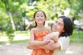 Portrait of happy Asian mother cuddle daughter and hugging teddy bear doll in the garden. Mom and child girl with love and Royalty Free Stock Photo