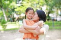 Portrait of happy Asian mother cuddle daughter and hugging teddy bear doll in the garden. Mom and child girl with love and Royalty Free Stock Photo