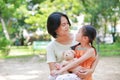 Portrait of happy Asian mother cuddle daughter and hugging teddy bear doll in the garden. Mom and child girl with love and Royalty Free Stock Photo