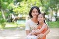 Portrait of happy Asian mother cuddle daughter and hugging teddy bear doll in the garden. Mom and child girl with love and Royalty Free Stock Photo