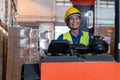 Portrait of happy Asian old man working in warehouse and sitting on forklift work with positive emotion. Royalty Free Stock Photo