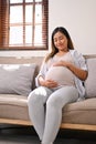 Portrait of happy Asian pregnant woman relaxes on the sofa in her living room Royalty Free Stock Photo