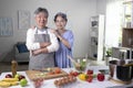 Asian senior couple preparing food in the kitchen. Retired people cooking meal at home, looking at camera Royalty Free Stock Photo