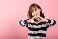 Portrait of a happy Asian lady with a confident smile, making a heart symbol Royalty Free Stock Photo