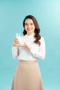 Portrait of a happy Asian woman drinking a glass of milk. Standing in front of a blue wall Royalty Free Stock Photo
