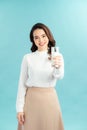 Portrait of a happy Asian woman drinking a glass of milk. Standing in front of a blue wall. Royalty Free Stock Photo