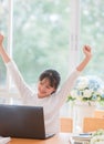 Portrait of happy Asian woman manager sitting at her laptop computer in work office and raised hands up with smiling because Royalty Free Stock Photo