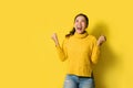 Portrait of a happy Asian woman screaming an excited and celebrating success isolated over yellow background. Succeed Royalty Free Stock Photo