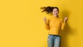 Portrait of a happy Asian woman screaming an excited and celebrating success isolated over yellow background. Succeed Royalty Free Stock Photo