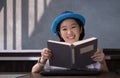 Happy Asian woman smiling and looking at camera while reading book in vintage living room Royalty Free Stock Photo