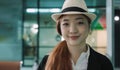 Portrait of happy Asian woman tourist wearing straw hat standing smiling and looking at camera in airport terminal Royalty Free Stock Photo