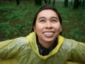 Portrait of Happy Asian woman wearing yellow raincoat stand in rain Royalty Free Stock Photo