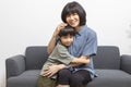 Asian woman and her little son hugging and sitting on sofa at home.