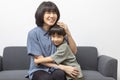 Asian woman and her little son hugging and sitting on sofa at home.