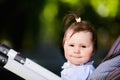 Portrait of the happy baby girl in a stroller in the city park at sunshiny day. Royalty Free Stock Photo