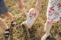 Portrait of happy baby holding hands of mother and father and making his first steps in nature at sunlights Royalty Free Stock Photo