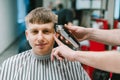 Portrait of happy barber shop customer cutting hair at professional male hairdresser, looking at camera and smiling. Barber`s han
