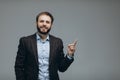 Portrait of a happy bearded businessman pointing finger away over white background Royalty Free Stock Photo