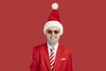 Portrait of happy bearded man wearing red suit, sunglasses and funny Christmas hat Royalty Free Stock Photo