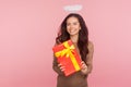 Portrait of happy beautiful angelic young woman with halo holding big present and smiling to camera, satisfied with gift Royalty Free Stock Photo