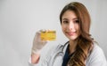 Portrait of happy beautiful Asian woman doctor in white gown with stethoscope standing hold credit card in office at hospital Royalty Free Stock Photo