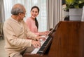 Portrait of happy beautiful Asian woman and her father sitting playing piano and singing together having fun and enjoying in Royalty Free Stock Photo