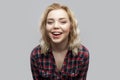 Portrait of happy beautiful blonde young woman in casual red checkered shirt standing, laughing and looking at camera with toothy Royalty Free Stock Photo
