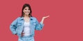 Portrait of happy beautiful brunette young woman with makeup in denim casual style standing, hand on copyspace and looking at Royalty Free Stock Photo