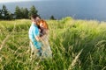 A portrait of happy beautiful couple on nature with big lake. Young couple hugging on bank of river. Man hugging red hair girl