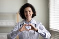 Happy beautiful middle aged doctor making heart gesture. Royalty Free Stock Photo