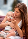 Portrait of happy beautiful mother feed her baby summer outdoors in park. Royalty Free Stock Photo