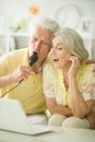 Happy beautiful senior couple singing karaoke with laptop at home Royalty Free Stock Photo