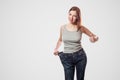 portrait of happy beautiful slim waist of young woman in big jeans and gray top showing successful weight loss Royalty Free Stock Photo