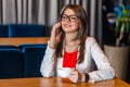 Portrait of happy beautiful stylish brunette young woman in glasses sitting talking on mobile smart phone and toothy smile Royalty Free Stock Photo