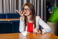 Portrait of happy beautiful stylish brunette young woman in glasses sitting, toothy smile, holding her mobile smart phone and Royalty Free Stock Photo