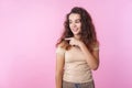 Portrait of happy beautiful teen girl pointing to the side and smiling, showing empty copy space. studio shot isolated, pink Royalty Free Stock Photo