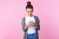 Portrait of happy beautiful teenage girl using cell phone, feeling excited of chatting with friends. pink background Royalty Free Stock Photo