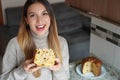 Portrait of happy beautiful woman holding a slice of Panettone traditional Italian cake for Christmas with raisins and candied