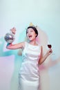 Portrait of a happy beautiful woman in white dress having a party and drinking champagne while standing with disco ball isolated Royalty Free Stock Photo