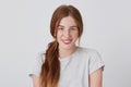 Portrait of happy beautiful yong woman with long red hair and freckles smiles and looks directly in camera isolated over white Royalty Free Stock Photo