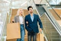 Portrait of happy beautiful young couple holding shopping paper bags with purchases and walking down stairs, holding Royalty Free Stock Photo