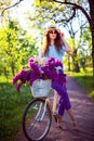 Beautiful young girl with vintage bicycle and flowers on city background in the sunlight outdoor. Royalty Free Stock Photo