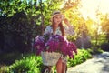 Portrait of a happy beautiful young girl with vintage bicycle and flowers on city background in the sunlight outdoor Royalty Free Stock Photo