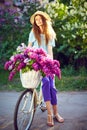 Portrait of a happy beautiful young girl with vintage bicycle and flowers on city background in the sunlight outdoor Royalty Free Stock Photo