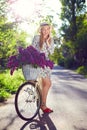 Portrait of a happy beautiful young girl with vintage bicycle and flowers on city background in the sunlight outdoor Royalty Free Stock Photo