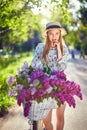 Portrait of a happy beautiful young girl with vintage bicycle and flowers on city background in the sunlight outdoor Royalty Free Stock Photo