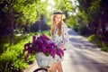 Portrait of a happy beautiful young girl with vintage bicycle and flowers on city background in the sunlight outdoor Royalty Free Stock Photo