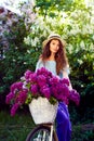 Portrait of a happy beautiful young girl with vintage bicycle and flowers on city background in the sunlight outdoor Royalty Free Stock Photo